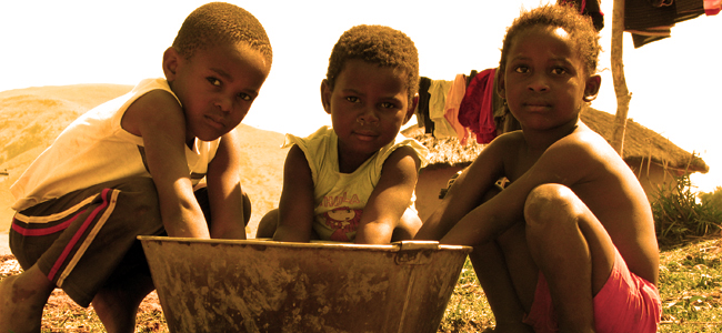 three children playing with water in a tub